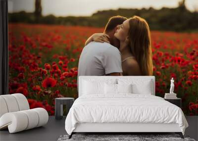 Loving couple in the poppy field. 
The guy gently kisses his girlfriend in the neck. Loving couple hug one another during romantic date in poppy field. Enjoying time together. Passion. Wall mural