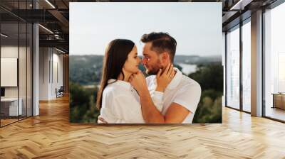 Profiles of romantic couple looking at each other on background of beautiful landscape. Close-up of a young couple. Wall mural