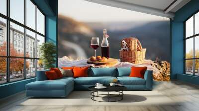 Romantic picnic with basket with baguette, red wine and croissants in the mountain at sunny day. Wall mural