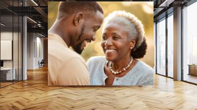 Close up candid portrait of African mother and son smiling at each other having a beautiful moment, happy young adult son and mature middle aged woman bonding, outdoor shot at golden hour Wall mural