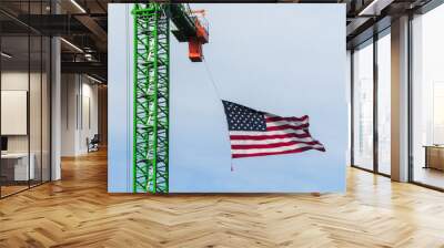 A waving American flag hangs from a construction tower crane Wall mural