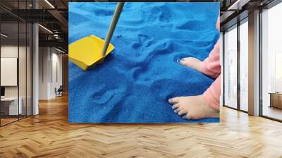 Small child feet playing with shovel in blue sand Wall mural