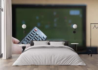 Male hand with a TV remote control close-up. Football fan watching match. Soft focus Wall mural