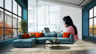 Portrait of a young Asian female adult learner studying online at home during Coronavirus or COVID-19  pandemic. Businesswoman work with laptop at home in house corridor and garden Wall mural