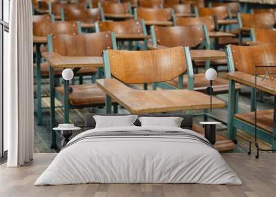 Wooden lecture chairs arranged in the classroom. Empty college classroom with many vintage wooden lecture chairs but no students. Back to school concept.  Wall mural