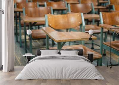 Wooden lecture chairs arranged in the classroom. Empty college classroom with many vintage wooden lecture chairs but no students. Back to school concept.  Wall mural