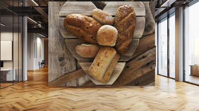 Assorted bread loaves, baps, buns and bakery on wooden heart. Wall mural