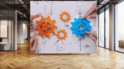 A collage of hands pointing at two gears, one orange and the other blue with check marks on them Wall mural