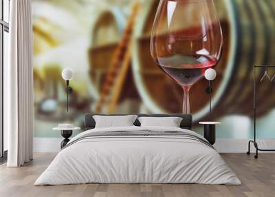 Glass of wine and wooden barrels in winery Wall mural