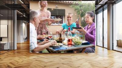 Blond woman serving healthy food pasta salad to Friends having a great time at dinner party Wall mural