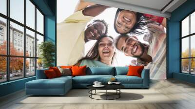 Group of young friends standing in circle and smiling to camera - Happy diverse students having fun hugging together Wall mural