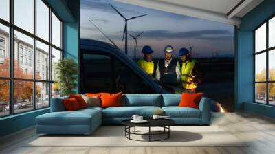 Team of technicians and engineer working in wind turbine farm at night, planing renewable energy ecology project Wall mural