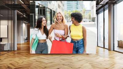 Three girls shopping and walking in the city in summer vacations. Cheerful multiracial women having fun in the weekend Wall mural