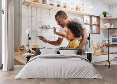 African Father and son make video call with digital tablet with family while cooking in kitchen Wall mural