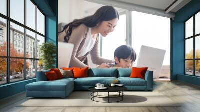 Happy young Chinese woman teacher helping Asian school kid boy student using laptop computer education in elementary class lesson at school. Wall mural