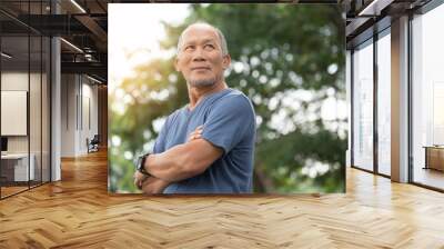 Portrait of Asian Elderly man with arms crossed relaxing over nature background. Happy confident Senior person in blue shirt standing at the park. Wall mural