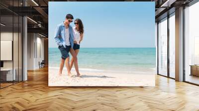 Portrait of Romantic Young couple in casual wear sun glasses walking at the beach with blue sky. Wall mural