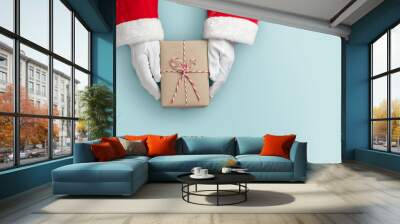 Top view of Santa claus hands is holding a brown gift box or present box over blue isolated background. Wall mural