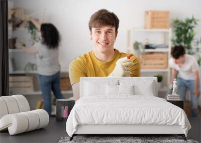 Portrait of young man holding cleaning products Wall mural