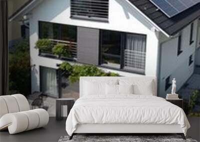 Modern white house with solar panels on the roof and a patio with a table and chairs. Wall mural