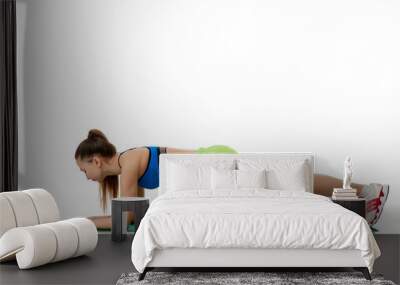 a girl in sports clothes on a Mat sports poses on a white background Wall mural