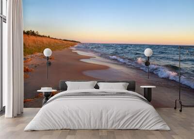 Golden sunset on a wide sandy beach along the coast of Lake Michigan as waves crash onto the shore. Wall mural