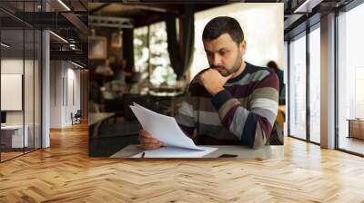 Young worried man reading a document Wall mural