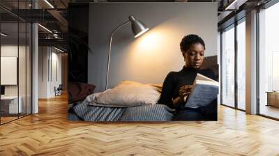 Woman reading a book from her comfortable sofa Wall mural