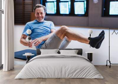 An active senior man is smiling while doing a sit up on a mat Wall mural