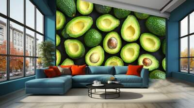 Close-up of several green avocados some with one half open. Green background. Wall mural