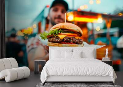 A man presenting a large, juicy burger in front of a food truck, with soft edges and a blurred background creating a lively, contemporary scene Wall mural