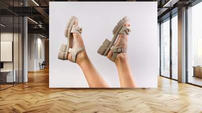 Banner advertising shoes on female legs. Place for text. Sandals on female feet. Shoes on the fashion platform. Summer trend. Photo of sandals on women's feet on a white background Wall mural