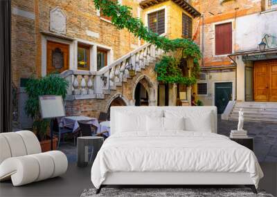 Old street with tables of restaurant in Venice, Italy. Architecture and landmark of Venice. Cozy cityscape of Venice. Wall mural