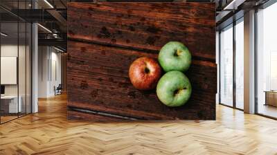 Fresh apples, autumn harvest. Three apples - two green and one red-lie on a wooden table. Fresh apples on a wood textured brown background, mahogany material. Wall mural