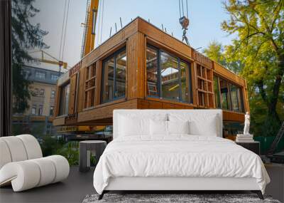 Modular wooden building module being lifted by a crane at a construction site. Sustainable architecture and urban development concept. Design for poster, banner, and construction industry Wall mural