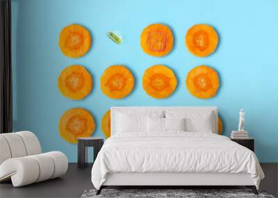 Sliced carrot pattern with capsule on pastel blue background. Fish oil pills. Medicine healthcare or beauty concept. Flat lay style. Wall mural