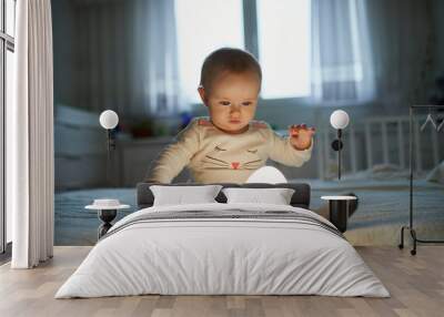 Adorable baby girl playing with bedside lamp in nursery Wall mural