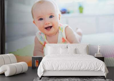 baby girl lying on colorful play mat on the floor Wall mural