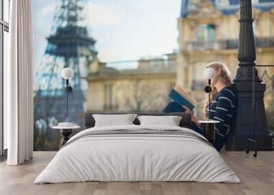 Beautiful young woman in Paris, reading a book Wall mural