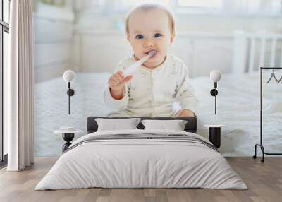 Cute little girl with toothbrush in pyjamas on bed Wall mural