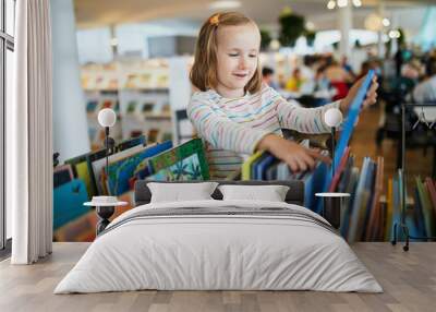 Five year old girl selecting a book in municipal library Wall mural