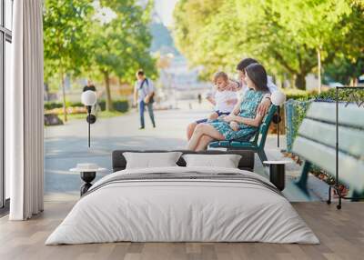 Happy family of three sitting on the bench near the Eiffel tower Wall mural