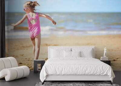 Preschooler girl having fun on the sand beach at sea coast in Noordwijk, the Netherlands Wall mural