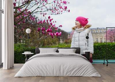 Preschooler girl looking at pink magnolia in full bloom on a street of Paris, France Wall mural