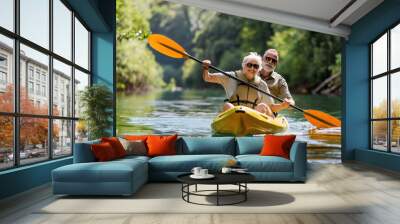 Senior couple kayaking on the river. Healthy elders enjoying summer day outdoors. Sportive people having fun at the nature. Active retirement concept Wall mural