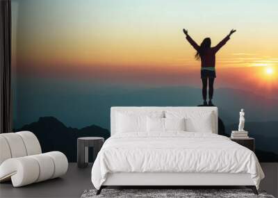 Silhouette of woman standing on top of the mountain looking at sunset or sunrise. Wall mural