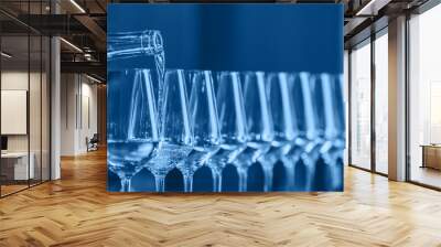 Wine glasses in a row. Pouring wine. Buffet table celebration of wine tasting. Nightlife, celebration and entertainment concept. Horizontal, cold toned image Wall mural