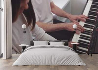 A teenage pianist and her dad play the piano, touching their fingers to the black and white keys to create the rhythm of the melody. People. Child development and entertainment. Art. Education Wall mural