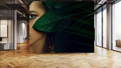 A beautiful tanned young woman with natural makeup and wet hair stands in the jungle among exotic plants. Tropical plants, nature. Wall mural