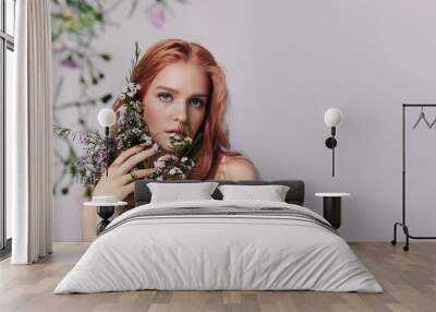 Portrait of a beautiful young woman with red hair and flowers near the face. Wall mural